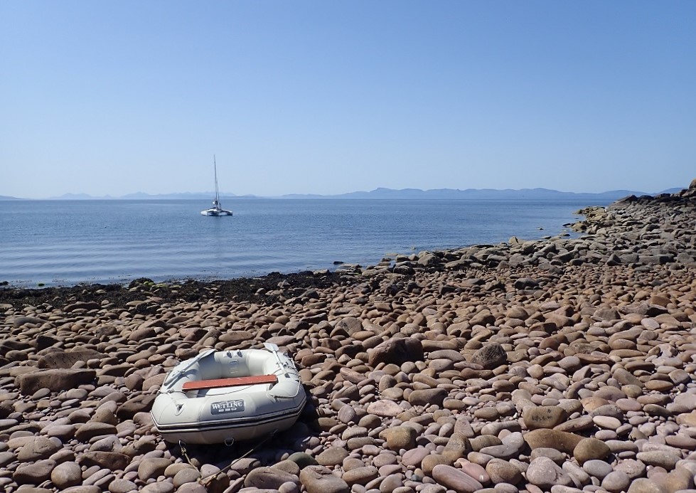 Dinghy on shore yacht at anchor scotland sailing